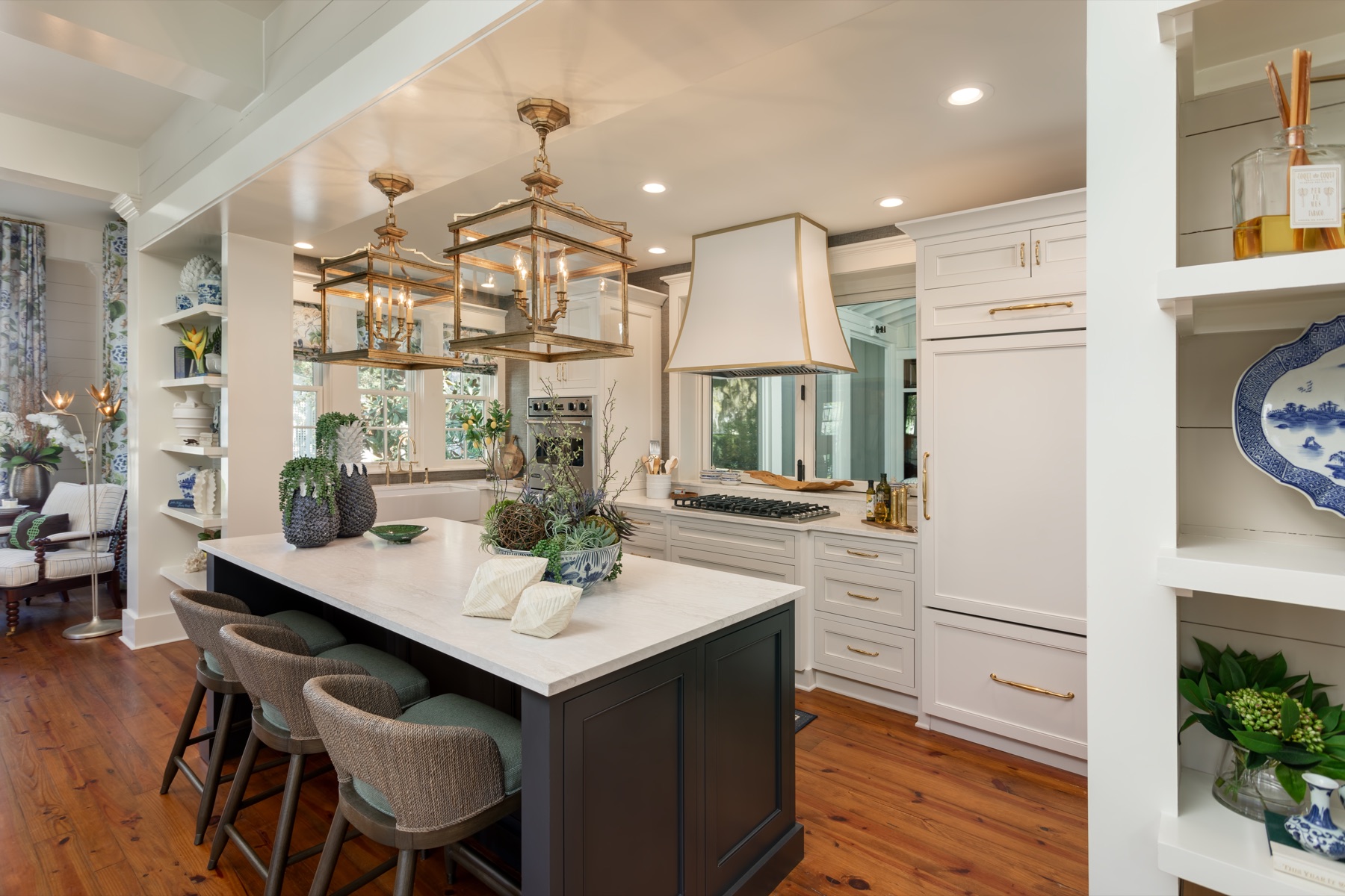 A renovated kitchen, white cabinetry and brass lanterns over a dark island